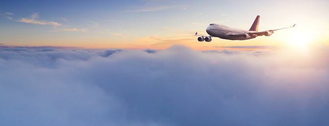Huge two-storey passengers commercial airplane flying above clouds in sunset light. Concept of fast travel, holidays and business.