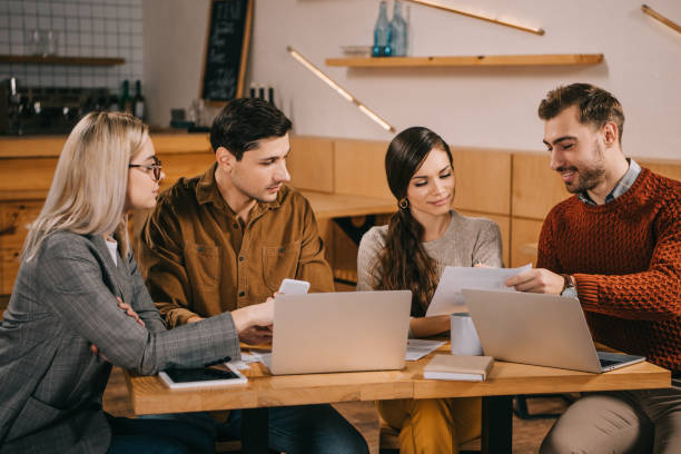 istock group of colleagues looking at paper near laptops while working in cafe 1093993704