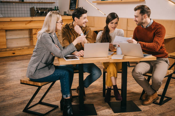 istock group of colleagues talking near laptops while working in cafe 1093993728