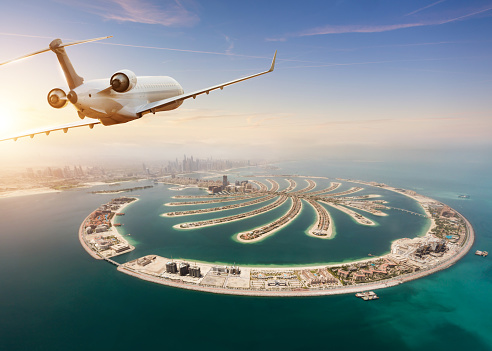 Private jet plane flying above Dubai city. Modern and fastest mode of transportation, business life and luxury style of life