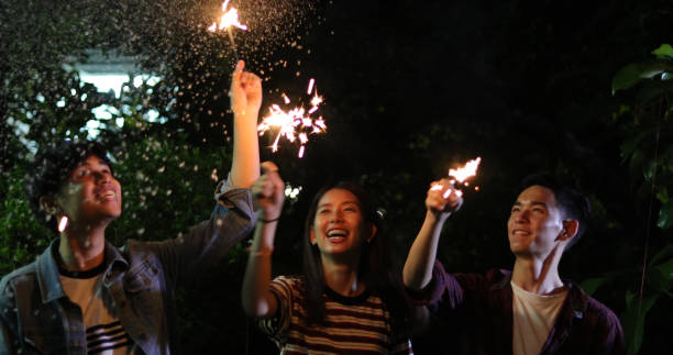 istock Happy Friends Burning Sparklers While Standing Against Sky At Night 1093996578