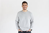 Young handsome man in oversized sweatshirt, standing isolated on gray background