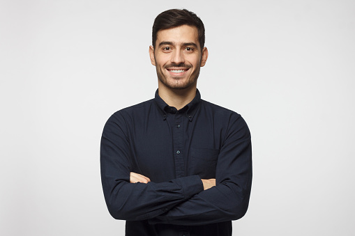 Portrait of casually dressed mature man smiling over white background with hand in pocket
