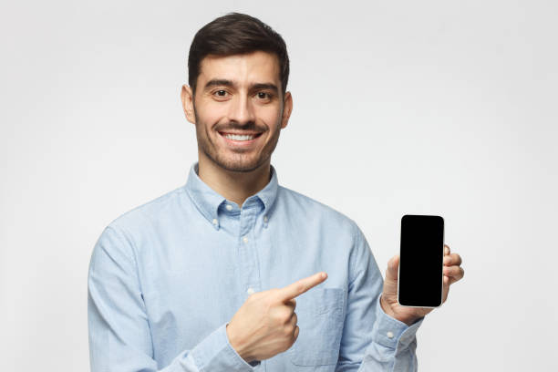 istock Young man holding mobile phone in hand and pointing to it with finger 1093999874