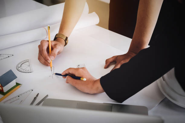 istock Negotiation or discussing, Young engineer reading of house or building structure on blueprint to present Customer. Architect or construction design concept. 1094014922