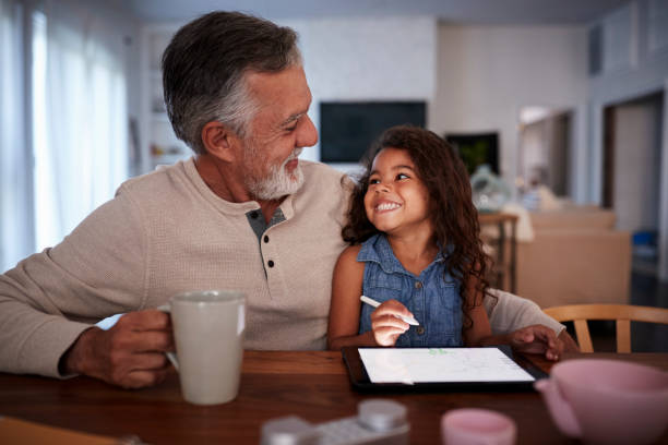 Senior Hispanic man with his granddaughter using tablet computer, looking at each other, front view Senior Hispanic man with his granddaughter using tablet computer, looking at each other, front view granddaughter stock pictures, royalty-free photos & images