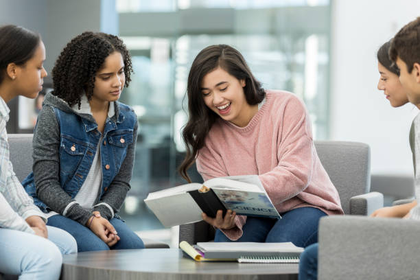 istock Teen girl reads textbook during group study session 1094020990