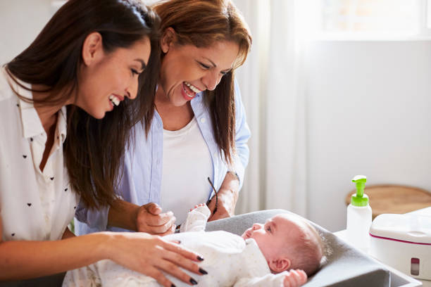 giovane nonna ispanica e figlia adulta che giocano con il figlio piccolo sul tavolo, da vicino - baby grandparent newborn grandmother foto e immagini stock