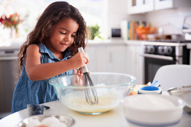 giovane ragazza ispanica fare una torta in cucina da sola, da vicino - cake batter foto e immagini stock