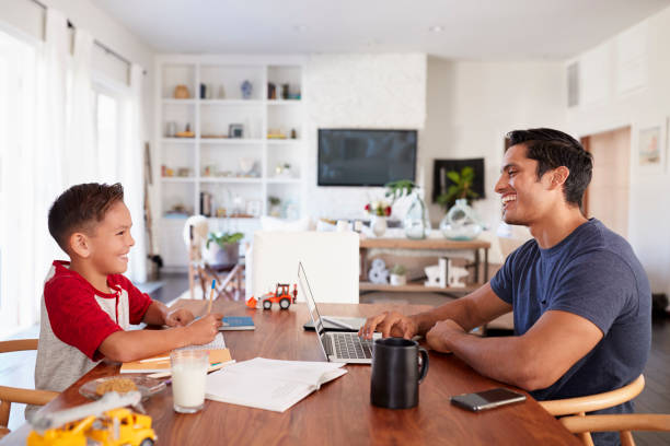 istock Hispanic father and son working at the dining room table smiling at each other, side view, close up 1094026906