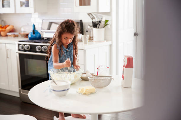 istock Young girl in the kitchen mixing cake mixture on her own, front view 1094028236