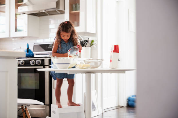 istock Young girl in the kitchen making cake mixture on her own, front view 1094028242
