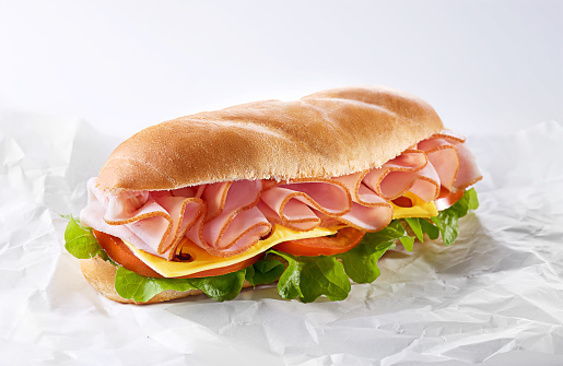 Salami sandwich made from bun, sliced ham and fresh letttuce, tomato and cheese. Healthy breakfast. Copy space
