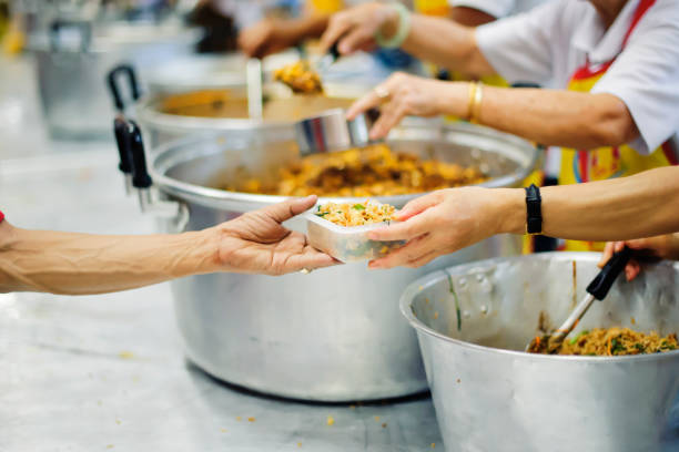 一緒に仲間の人間から共有を助けることが貧しい人々 に食糧を提供する: 飢饉と社会的不平等の概念 - pauper ストックフォトと画像