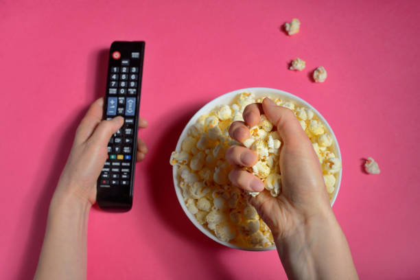 istock Top view of hands holding remote controller and popcorn bucket isolated 1094052920