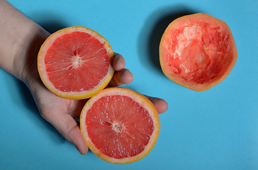 Half of grapefruit in hand on blue background