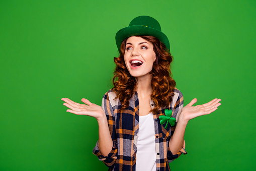 Close up photo of screaming she her lady meeting guests in own bar glad to see everybody looking to empty space wearing casual checkered plaid shirt leprechaun headwear isolated on green background