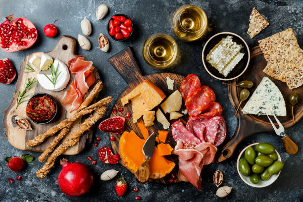 istock Appetizers table with italian antipasti snacks and wine in glasses. Brushetta or authentic traditional spanish tapas set, cheese variety board over black stone background. Top view, flat lay 1094054218