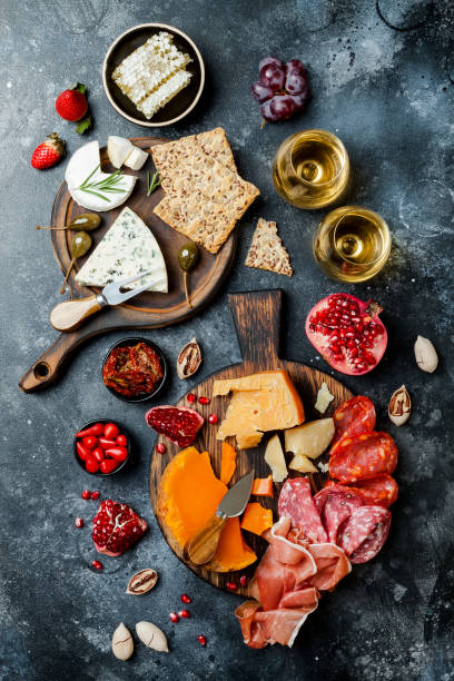 istock Appetizers table with italian antipasti snacks and wine in glasses. Brushetta or authentic traditional spanish tapas set, cheese variety board over black stone background. Top view, flat lay 1094057308