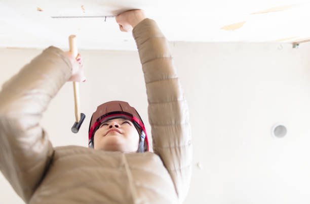 A young woman is hammering a nail to a wall