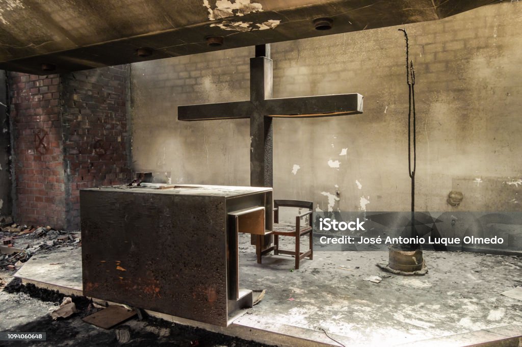 Beautiful altar and huge cross in a church or chapel destroyed by fire. Ruins of a recent burned religious place. Power of fire. Beautiful altar and huge cross in a church or chapel destroyed by fire. Ruins of a recent burned religious place with natural lights. Power of fire. Church Stock Photo