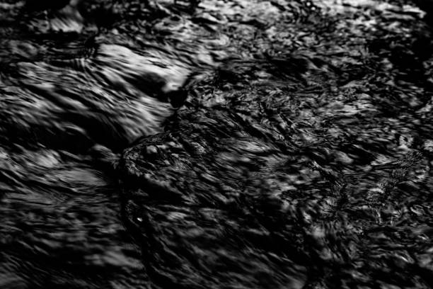 Dark Monochrome flowing water abstract background. Shot over a winter stream.