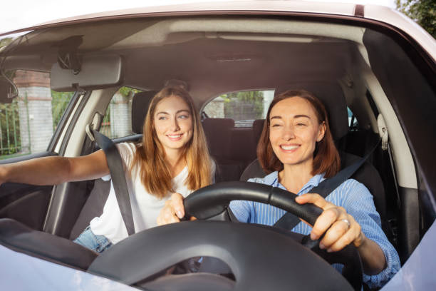 mother driving with daughter on passenger seat - vacations two generation family caucasian friendship imagens e fotografias de stock