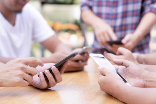 istock group of young man or friends playing online application game in modern touch screen mobile on wood table. 1094068268