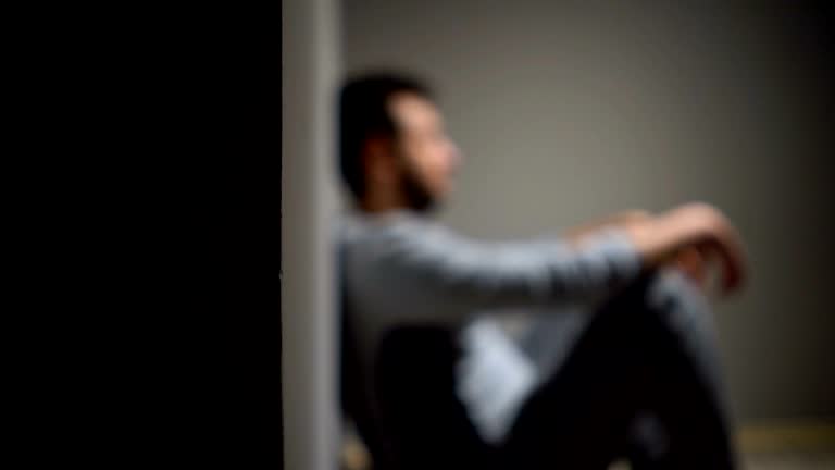 Young depressed man sitting on the floor. Depression, sadness, hardship, mental health issues concepts.
