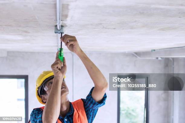 Electrician Wiring On Ceiling In Construction Site Stock Photo - Download Image Now - Electrician, Repairing, Electricity