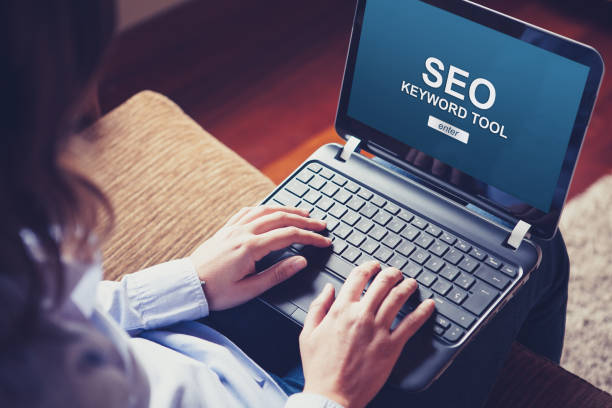istock SEO keyword tool in a laptop screen while woman types on the keyboard. 1094077856
