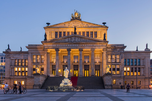 People walking in the Gendarmenmarkt square next to the Berlin Concert Hall (Konzerthaus Berlin) during sunset in the Mitte district of central Berlin city, Germany.