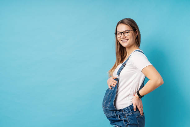 istock A pregnant young woman having a back ache standing over blue background in the studio 1094082448