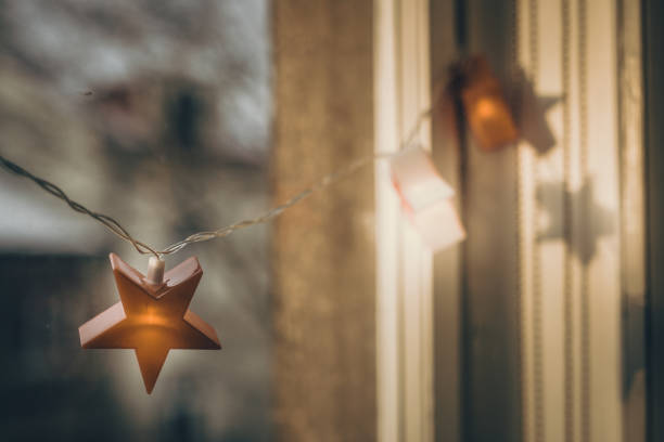 Christmas lights in shape of stars hanging on window in old tenement house. Christmas. City. Krakow in Poland. Locked down. Close shot