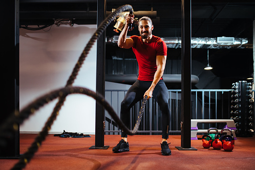 Man with battle ropes exercising at the gym
