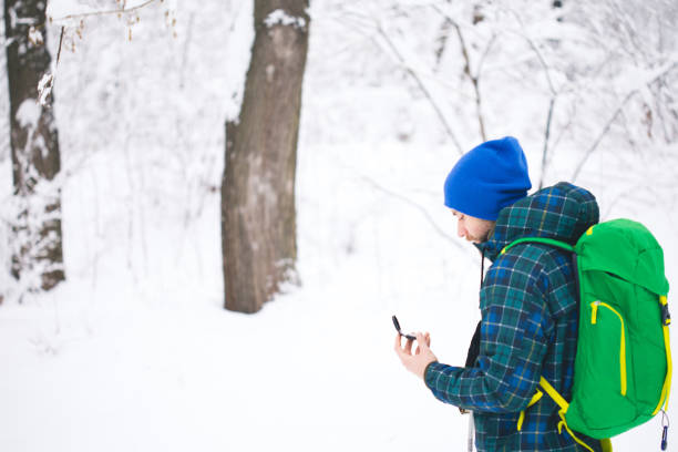 man searching direction with compass in winter snowy forest - orienteering planning mountain climbing compass imagens e fotografias de stock