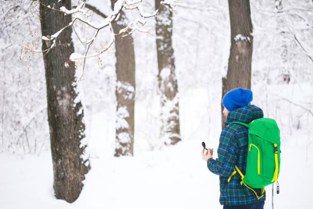 man searching direction with compass in winter snowy forest - orienteering planning mountain climbing compass imagens e fotografias de stock