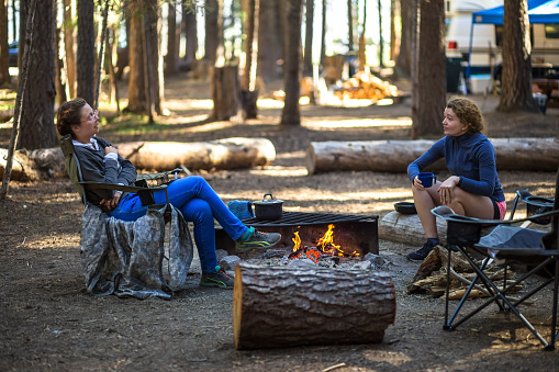 Two women cooking breakfast on a fire in a campsite in the woods in southern Oregon.