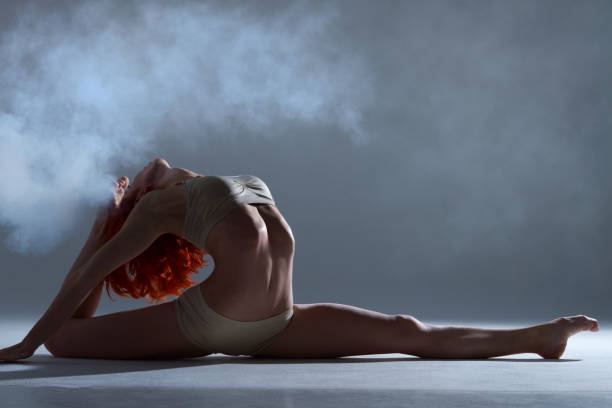 мышцы рыжая женщина танцует в дыму на изолированном фоне - the splits flexibility yoga teenage girls стоковые фото и изображения