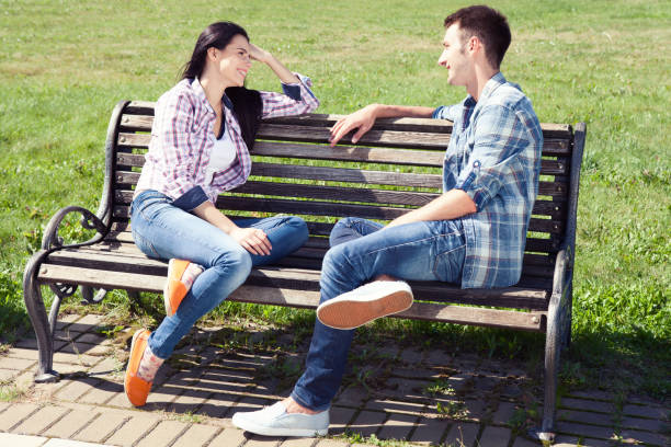 istock Couple relaxing on bench in front of skyline summer time. 1094120130