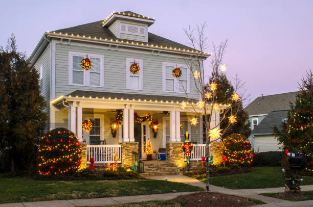 Homes Decorated for the Holidays McAdenville, North Carolina, USA - December 24, 2018: The quiet little town of McAdenville, which lies along the South Fork River in Gaston County N.C., comes alive in spectacular fashion each year as Christmas draws near. Almost overnight, the small textile town is transformed into “Christmas Town, USA.” A tradition since 1956, Victorian-style, brick and wood sided homes are beautifully and tastefully decorated for the Holiday Season. Taken just before sunset to include a beautiful and colorful sky as a backdrop to this festive image. christmas lights house stock pictures, royalty-free photos & images