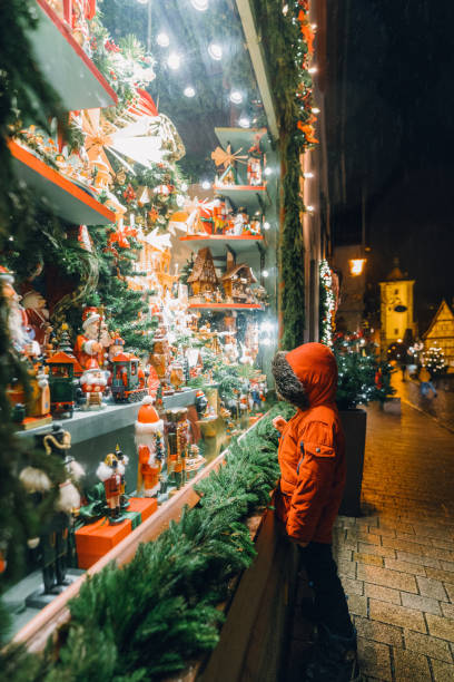 petit garçon regardant fenêtre store sur noël - window display toy store store christmas photos et images de collection