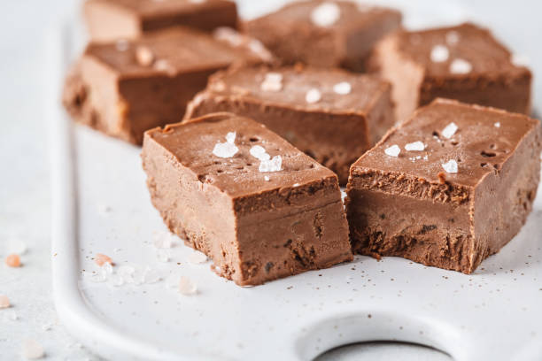 Raw vegan chocolate fudge on a white board. Raw vegan chocolate fudge on a white board. Healthy vegan food concept. fudge stock pictures, royalty-free photos & images