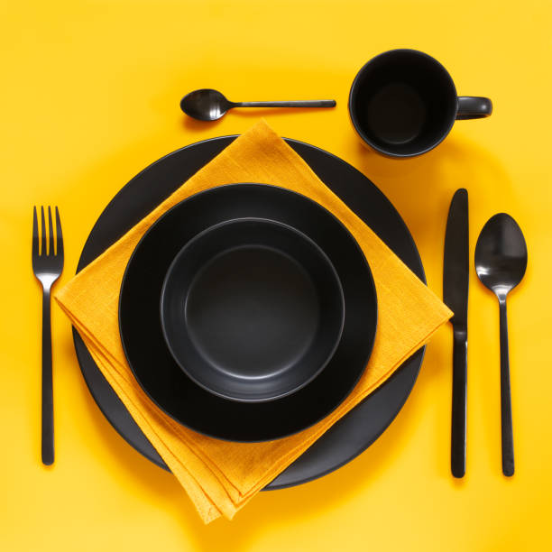 impostazione del tavolo giallo e nero - table knife silverware black fork foto e immagini stock