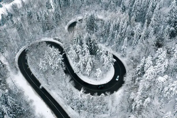 Driving on winter roads trough a forest winding road in the mountains