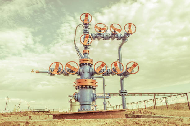 Wellheads with valve armature on a oil field. Wellhead with valve armature on a oilfield. Oil and gas industry concept. Industrial site background. Extraction of oil. Toned sepia. oil wellhead stock pictures, royalty-free photos & images