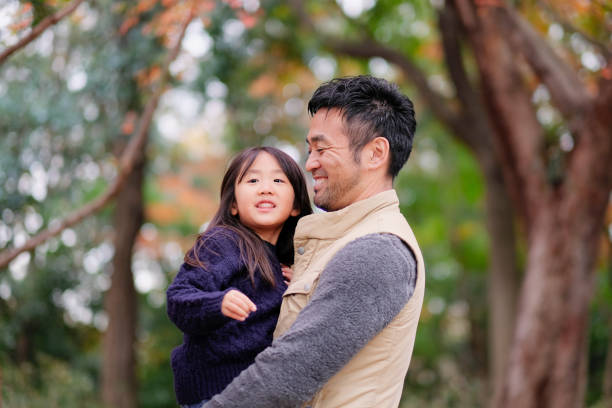 Father embracing daughter in park Father taking care of daughter in park role reversal stock pictures, royalty-free photos & images