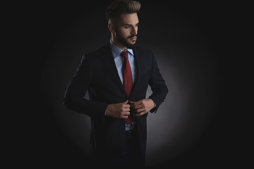 portrait of curious businessman in navy suit buttoning suit