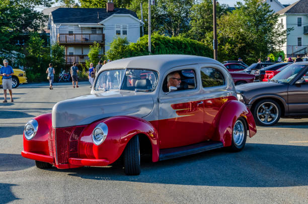 1940 Ford Tudor Sedan Dartmouth, Nova Scotia, Canada - August 10, 2017:  Mildly customized 1940 Ford Tudor backs into a parking spot at the A&W weekly summer Thursday cruise-in, Woodside Ferry Terminal parking lot, Dartmouth, Nova Scotia. On a pleasant summer evening people walk among the many classic cars. cruising hot rods stock pictures, royalty-free photos & images
