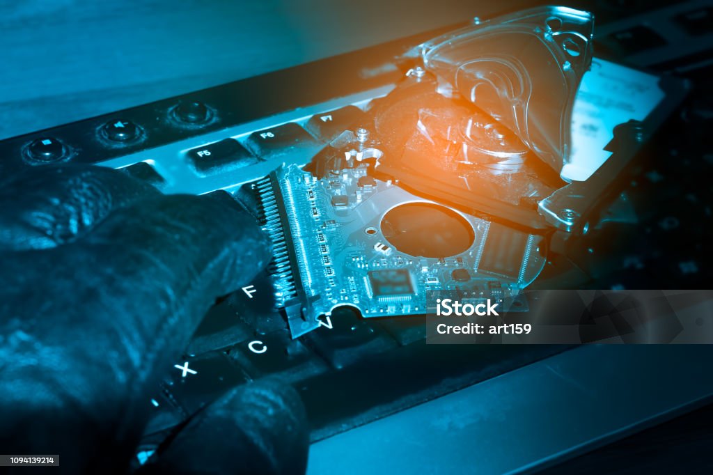Cybercriminal's hand on a keyboard. Hacked computer hard drive. Cybercrime concept Blue Stock Photo